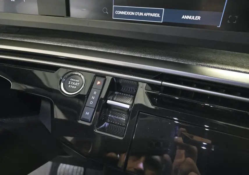 Gros plan sur la console centrale noire laquée du Peugeot 3008 Hybrid avec bouton start/stop et commande de boîte automatique.