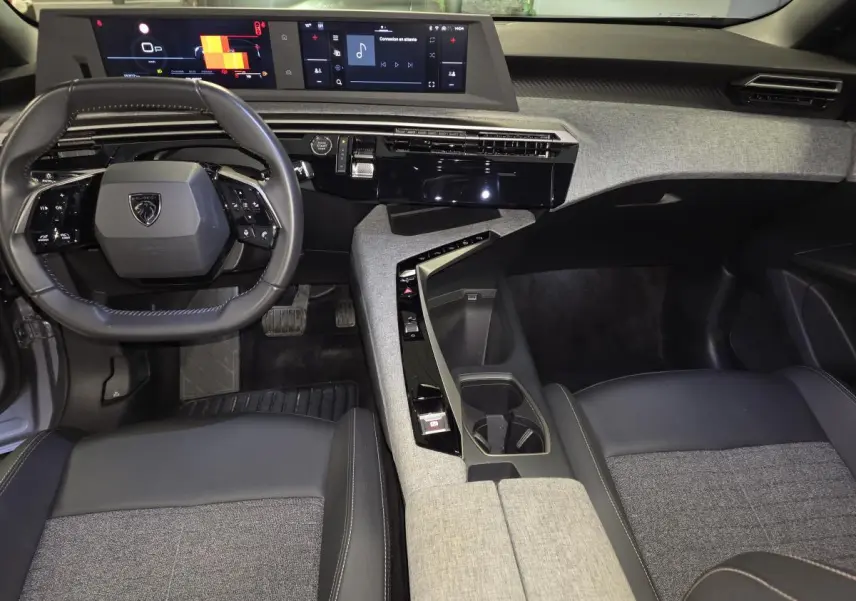 Vue intérieure avant du Peugeot 3008 gris 2025, mettant en valeur le tableau de bord tissu Rimini et double écran HD flottant.