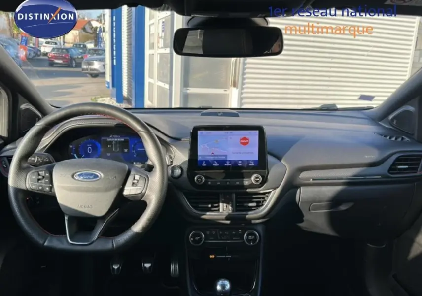 Vue intérieure avant du Ford Puma gris foncé, mettant en valeur le tableau de bord avec écran tactile et volant multifonction.