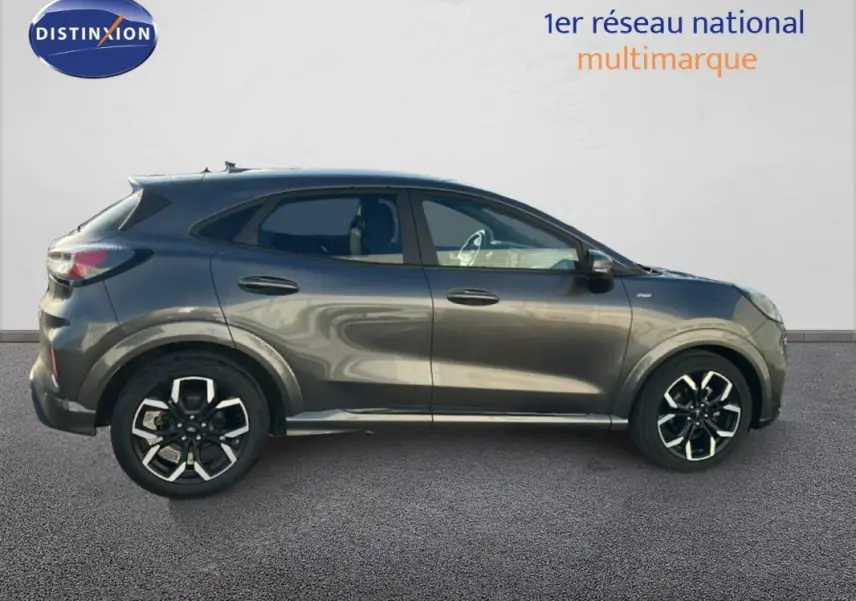Vue de profil côté gauche d'un Ford Puma gris foncé avec jantes alliage 18 pouces et vitres surteintées.