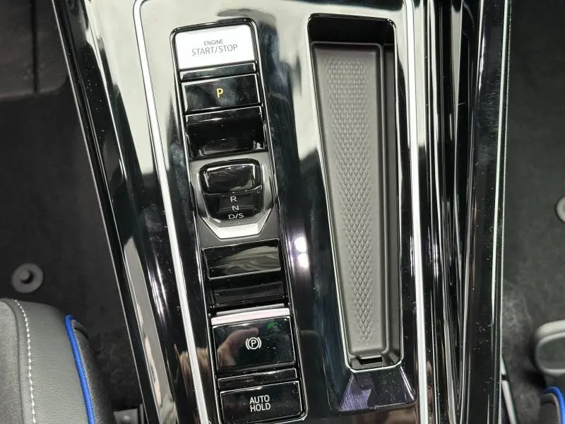 Gros plan sur la console centrale noire brillante de la Volkswagen Golf 2.0 TDI 150ch R-Line 2026 avec commandes boîte auto et frein électrique.