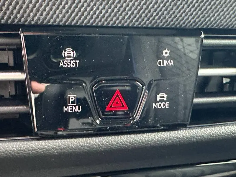Gros plan sur le panneau de commandes noir brillant avec bouton de détresse rouge dans une Volkswagen Golf gris 2.0 TDI R-Line 2026.