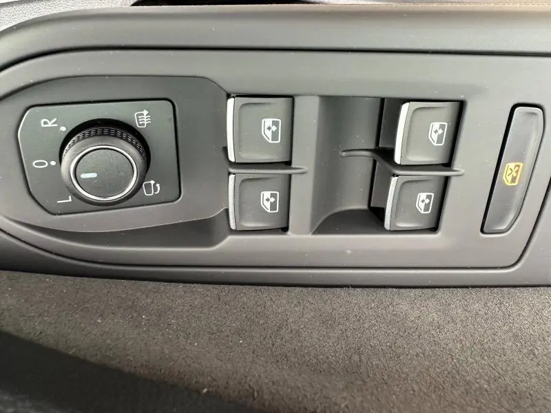 Gros plan sur les commandes de réglage des rétroviseurs et des vitres électriques d’une Volkswagen Golf gris 2.0 TDI R-Line 2026.