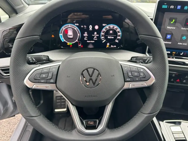 Vue rapprochée du volant multifonction gris de la Volkswagen Golf 2.0 TDI R-Line avec tableau de bord numérique.