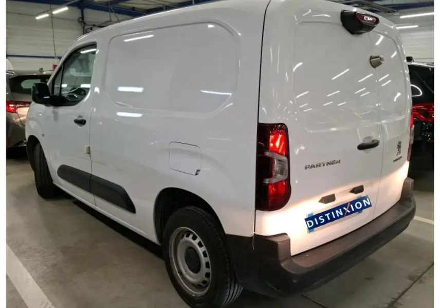 Vue 3/4 arrière droite d’un Peugeot Partner Fourgon blanc 2022 avec portes arrière fermées et protections noires.