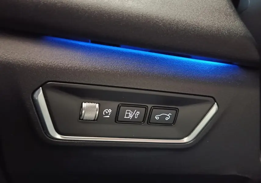 Détail intérieur du tableau de bord noir avec commandes de réglage et éclairage d’ambiance bleu du Link & Co 01 hybride rechargeable.