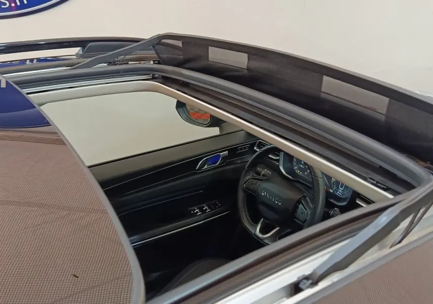 Vue intérieure par le toit ouvrant du volant cuir noir et tableau de bord digital du Lynk & Co 01 hybride rechargeable.