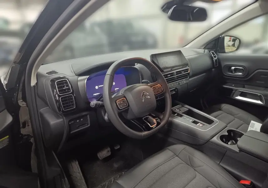 Vue intérieure côté conducteur du Citroën C5 Aircross Hybrid noir Perla, avec tableau de bord numérique et volant multifonctions.