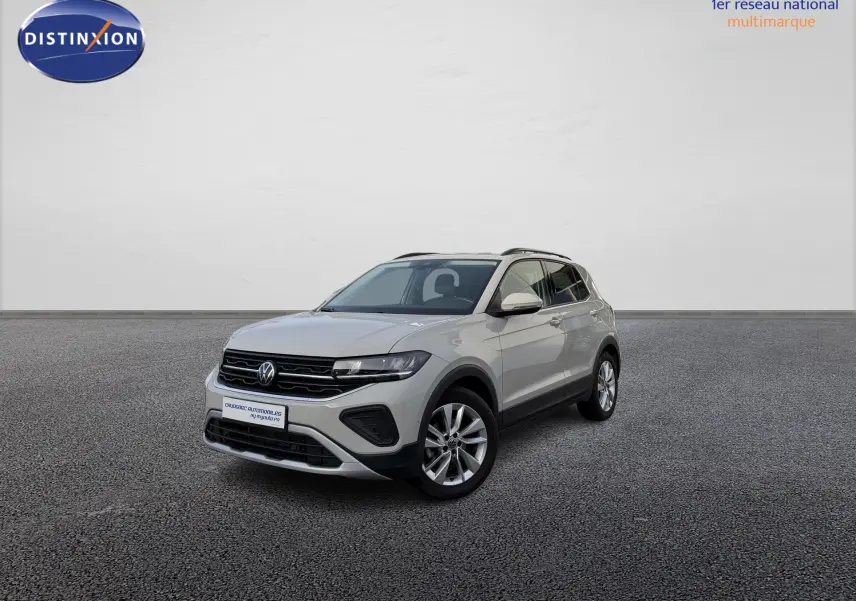Volkswagen T-Cross gris vue 3/4 avant droit sur sol gris, avec jantes alliage et calandre noire distinctive.