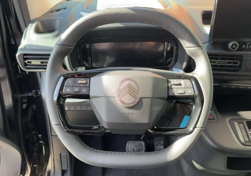 Vue rapprochée du volant cuir multifonctions gris du Citroën Berlingo Noir Perla Nera 2026 avec tableau de bord numérique.