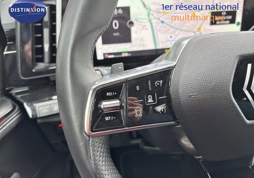 Gros plan sur le volant noir du Renault Austral 2023 avec commandes intégrées et écran de navigation en arrière-plan.