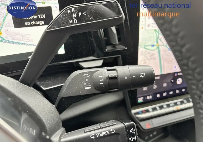 Gros plan sur les commandes au volant du Renault Austral 2023, avec écran tactile et navigation visible en arrière-plan.