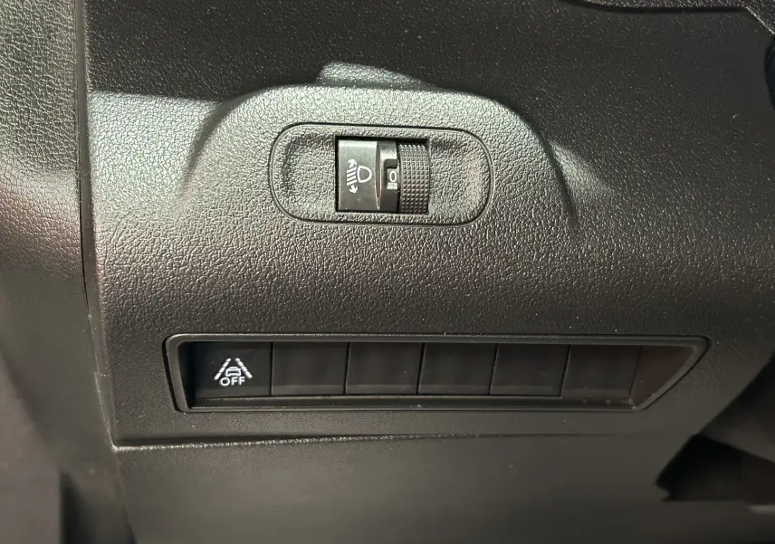 Détail du tableau de bord du Peugeot Rifter gris sable 2019, montrant les commandes d'éclairage et de désactivation de l'assistance.