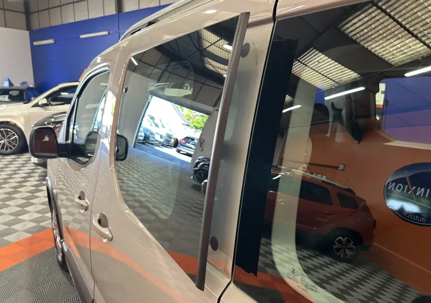 Vue latérale gauche rapprochée d'un Peugeot Rifter gris sable 2019 avec portes coulissantes en concession.