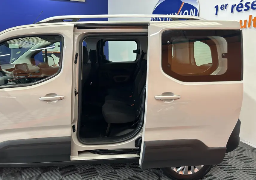 Vue latérale droite du Peugeot Rifter gris sable 2019 avec porte coulissante ouverte dévoilant l'intérieur à trois sièges.