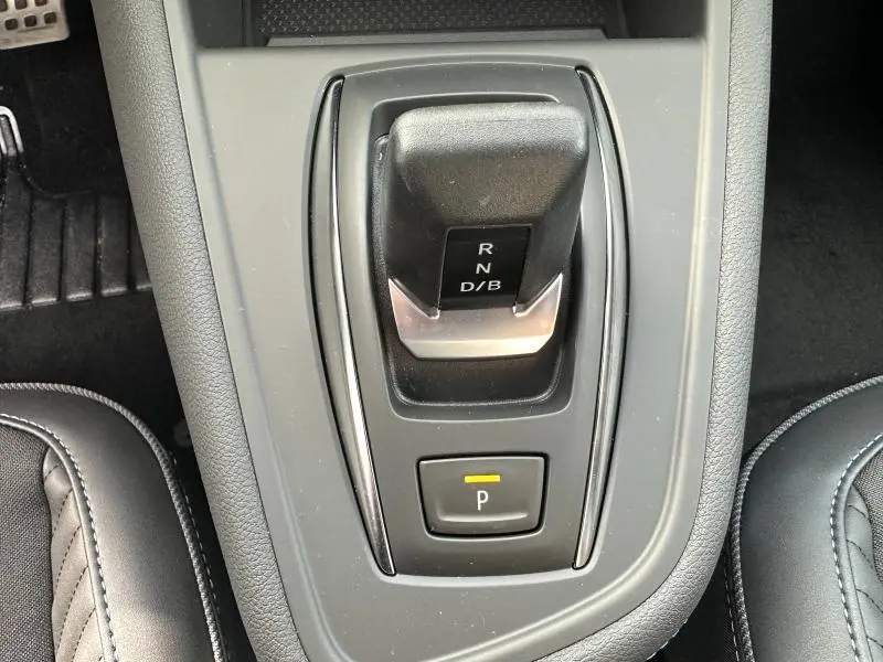 Vue rapprochée du levier de vitesses automatique noir et gris du Renault Captur 1.8 E-Tech hybride, avec bouton de parking éclairé.