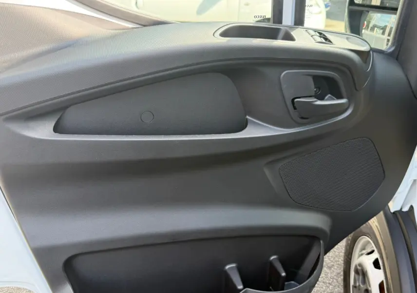 Vue rapprochée de la porte avant droite noire du fourgon Iveco Daily blanc, avec poignée et haut-parleur intégrés.