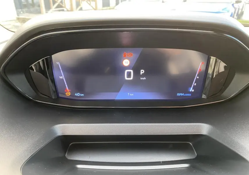 Vue rapprochée du tableau de bord numérique du Peugeot Partner Fourgon blanc, affichant la vitesse à 0 km/h.