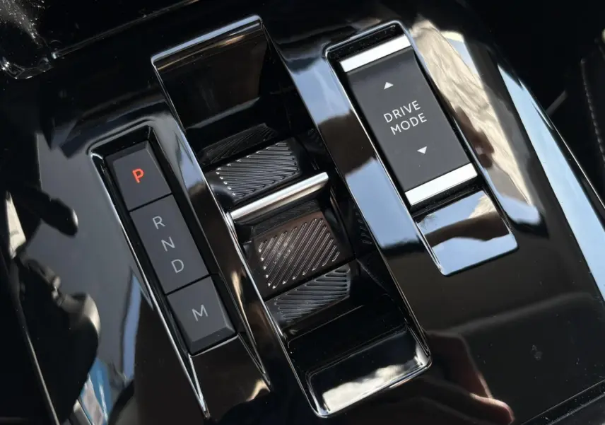 Vue rapprochée de la console centrale noire brillante avec commandes de boîte auto et sélection Drive Mode d'une Citroën C4 Hybrid 2025.