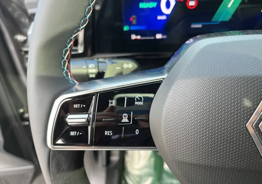 Gros plan sur les commandes à gauche du volant cuir multifonctions du Renault Austral gris schiste avec tableau de bord numérique.