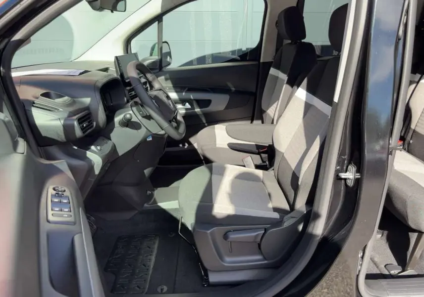 Vue intérieure côté conducteur du Citroën Berlingo noir perla nera, montrant les sièges tissu bicolores et le volant multifonctions.