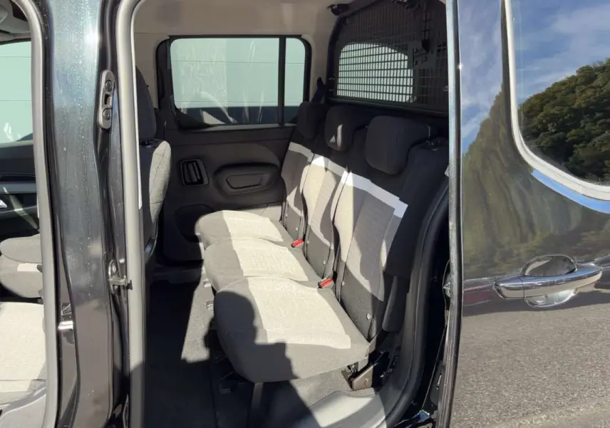 Vue latérale intérieure du Citroën Berlingo noir perla nera, montrant les trois sièges arrière indépendants en tissu clair.