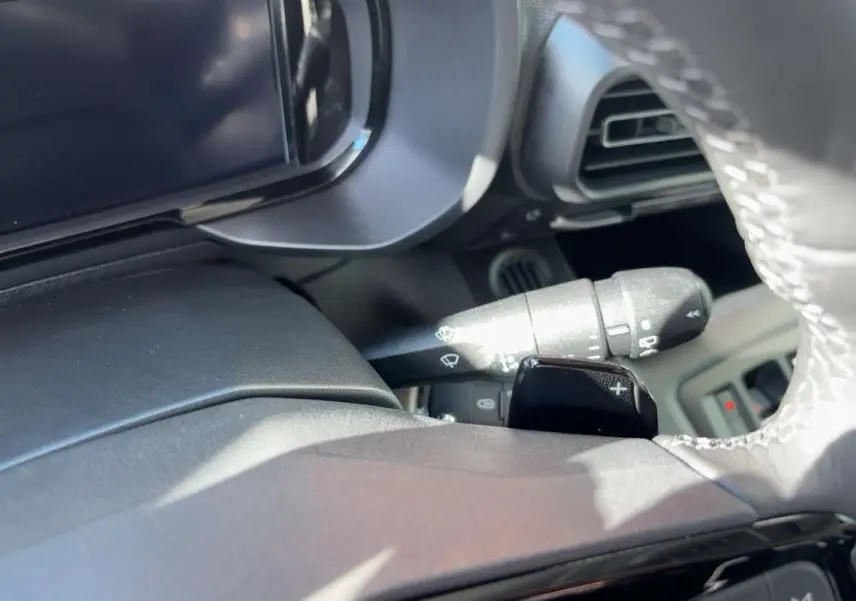 Gros plan sur le volant cuir et la commande de clignotant du Citroën Berlingo 2026, intérieur noir.