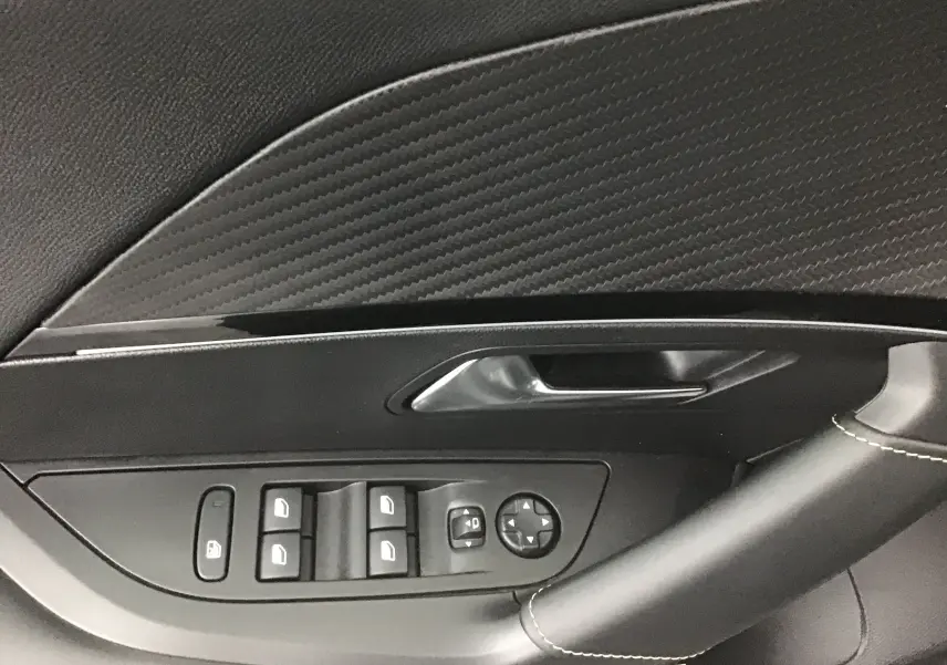 Détail de la porte côté gauche d'une Peugeot 2008 électrique 2022, avec commandes de vitres et revêtement noir texturé.