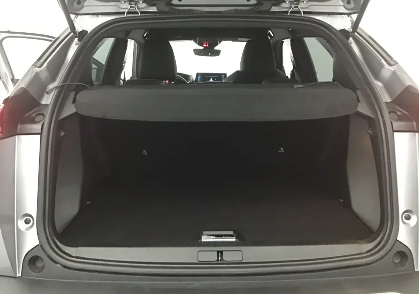 Coffre ouvert vu de l'arrière d'un Peugeot 2008 électrique gris Artense avec intérieur noir et tablette de séparation.