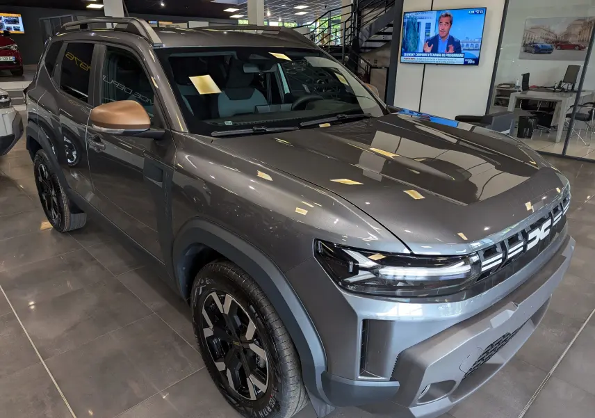Dacia Duster Mild Hybrid gris schiste vu en 3/4 avant droit, avec rétroviseur couleur bronze et jantes noires distinctives.