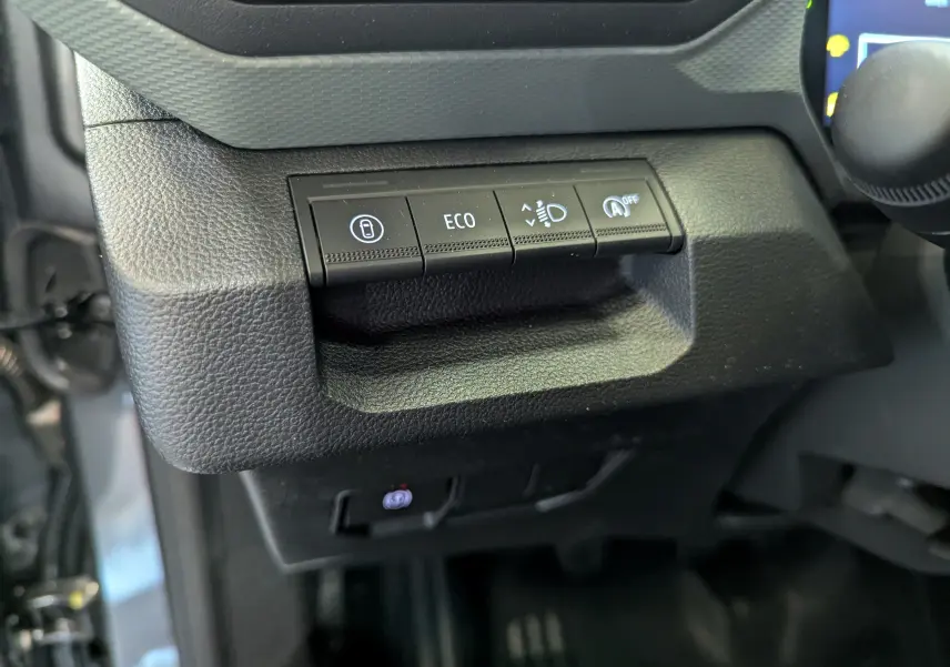Gros plan sur les commandes de fonctions ECO et assistance à la conduite dans le tableau de bord du Dacia Duster gris Schiste.
