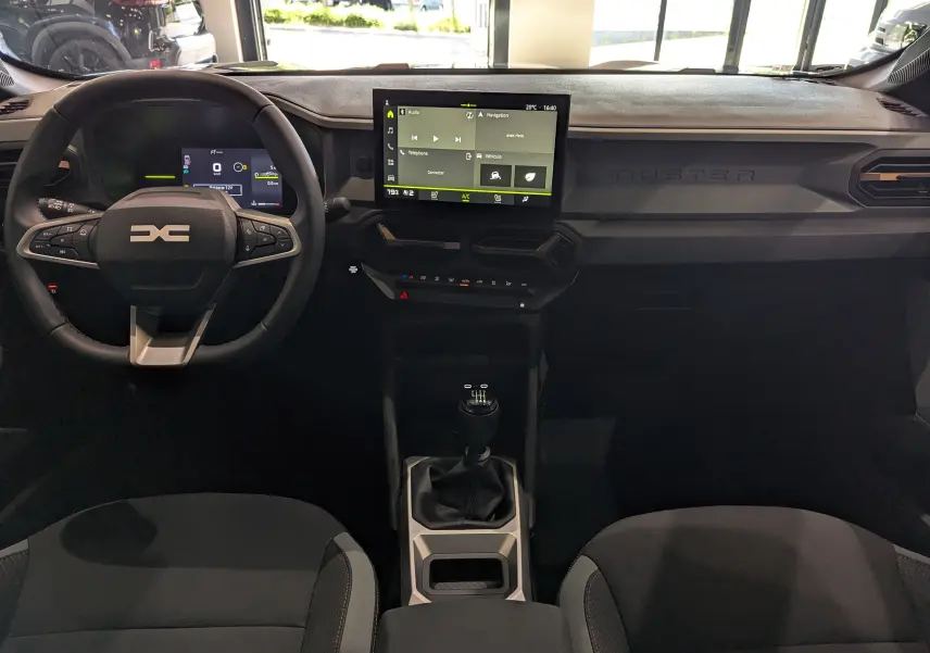 Intérieur du Dacia Duster 2025 avec tableau de bord moderne, écran tactile central et volant multifonction noir.