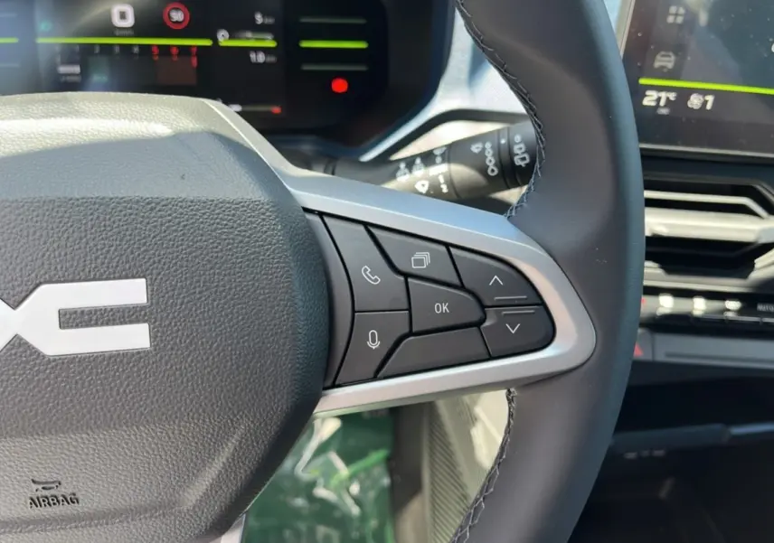 Gros plan sur le volant cuir avec commandes multifonctions du Dacia Bigster 2025, tableau de bord numérique en arrière-plan.