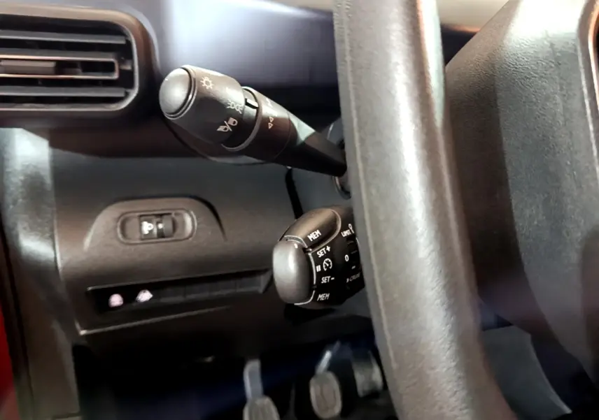 Gros plan sur les commandes de régulateur et éclairage derrière le volant du Peugeot Rifter BlueHDi 100 Allure 2019.