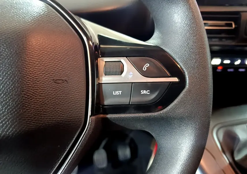 Gros plan sur les commandes du volant côté droit du Peugeot Rifter marron, avec boutons de téléphone et réglages audio.