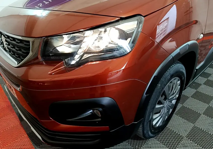 Gros plan sur l'avant droit marron du Peugeot Rifter 2019, mettant en valeur le phare LED et la calandre noire.