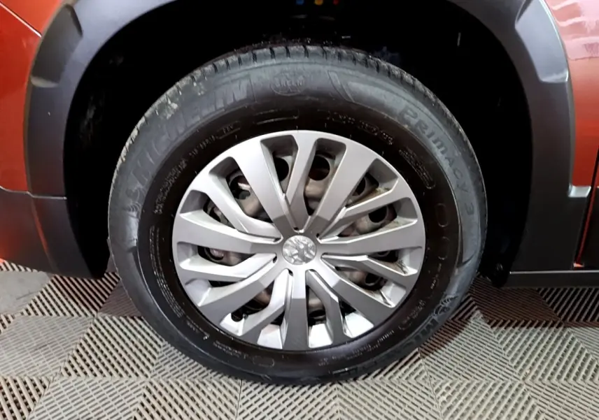 Gros plan sur la roue avant gauche du Peugeot Rifter marron, mettant en valeur la jante argentée et le pneu Michelin.