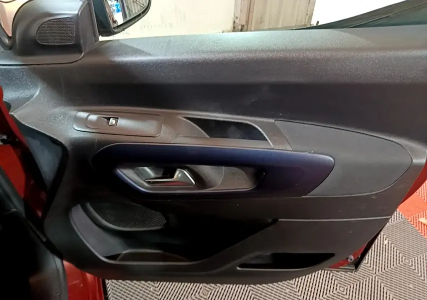 Gros plan sur la porte intérieure côté gauche du Peugeot Rifter 2019, avec poignée noire et bouton de vitre électrique.