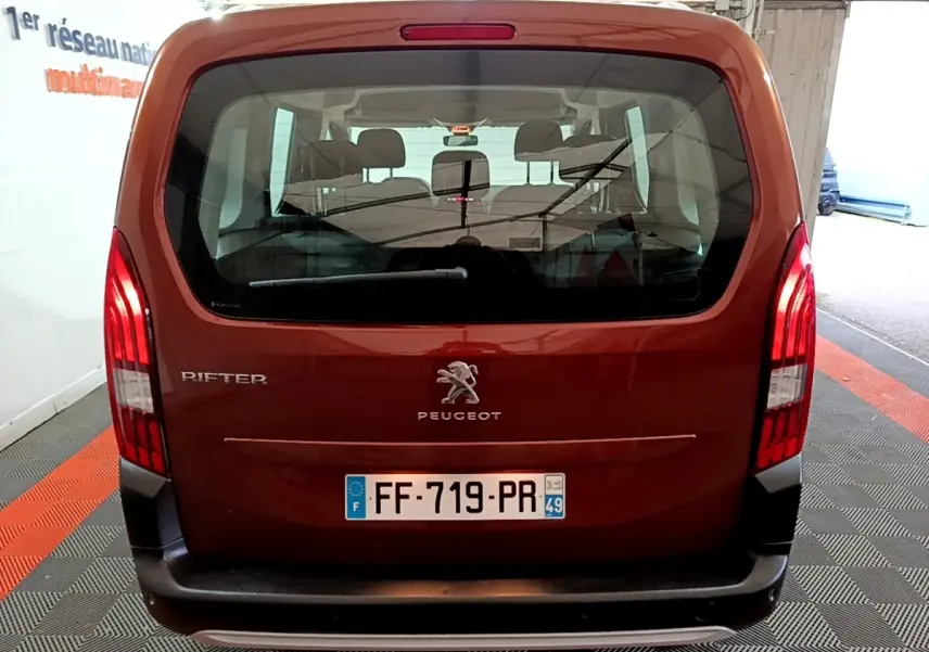 Vue arrière d'un Peugeot Rifter marron 2019 avec logo et feux verticaux allumés dans un garage.