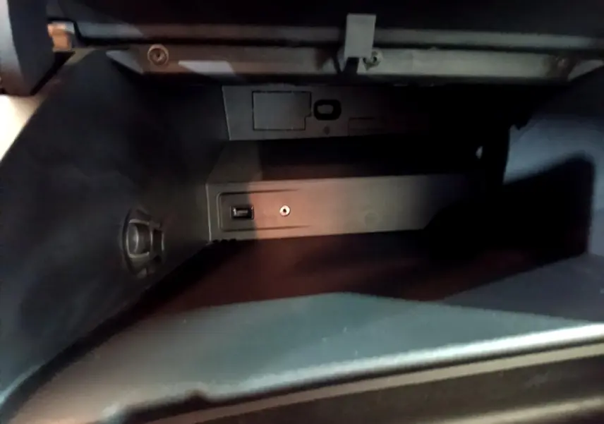 Vue rapprochée de la boîte à gants noire du Peugeot Rifter BlueHDi 100 Allure 2019 avec prise USB et prise auxiliaire.