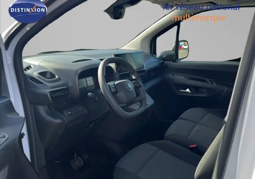 Vue intérieure côté conducteur du Citroën Berlingo blanc Icy 2025, tableau de bord et sièges noirs en tissu visibles.