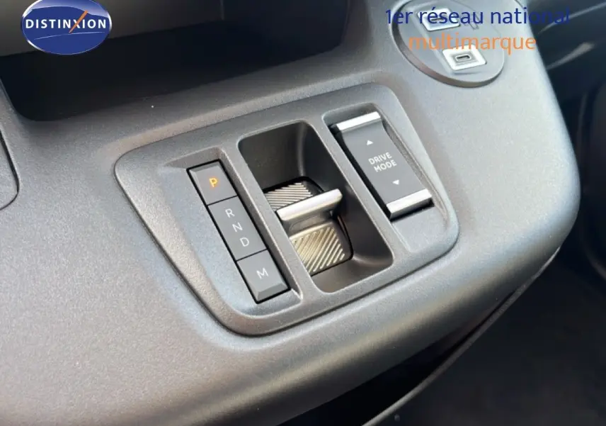 Gros plan sur la console centrale du Citroën Berlingo blanc, montrant la commande de boîte automatique et le bouton Drive Mode.