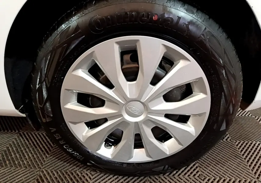 Gros plan sur la roue avant droite d'une Ford Fiesta blanche, avec jante en alliage et pneu Continental visible.