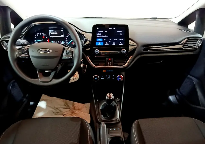 Vue intérieure avant de la Ford Fiesta 1.1 75ch COOL & CONNECT 2022, tableau de bord noir avec écran tactile et boîte manuelle.