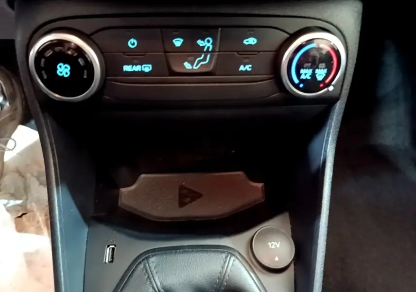 Vue rapprochée de la console centrale noire de la Ford Fiesta 2022, avec commandes climatisation et prise 12V visible.