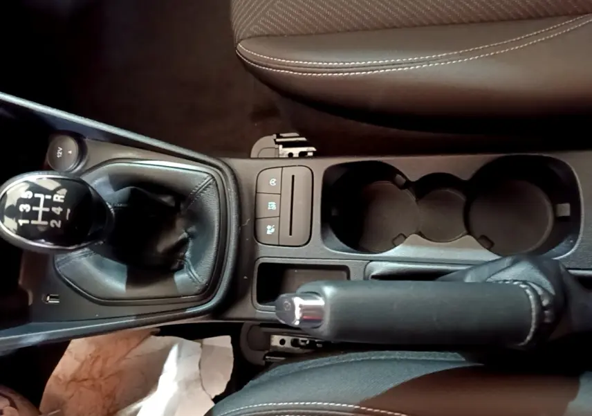 Vue plongeante sur la console centrale noire de la Ford Fiesta blanche, avec levier de vitesse manuel et frein à main.