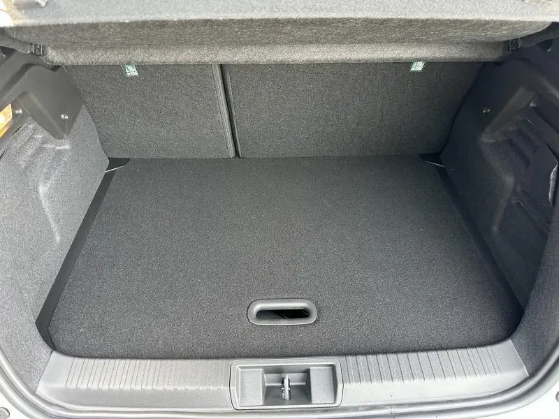 Coffre ouvert vu de face du Renault Captur 1.8 E-Tech 2026, espace de chargement avec tapis noir uniforme.