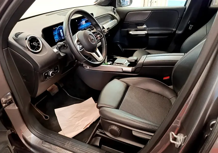 Intérieur avant droit du Mercedes GLB 200 d Business Line 2021 gris foncé, avec tableau de bord numérique et volant cuir.