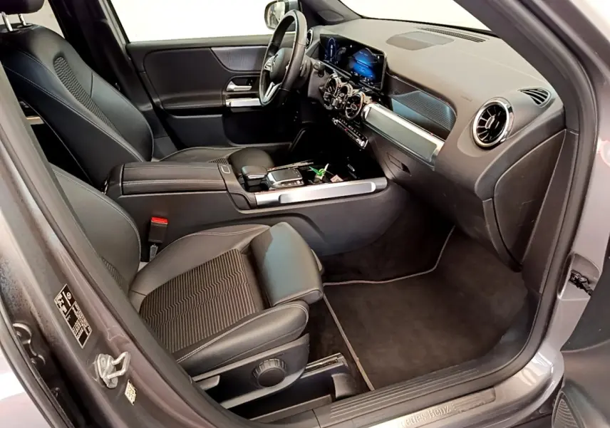 Vue intérieure côté passager avant du Mercedes GLB 200 d Business Line gris foncé, avec tableau de bord digital et sièges en cuir noir.