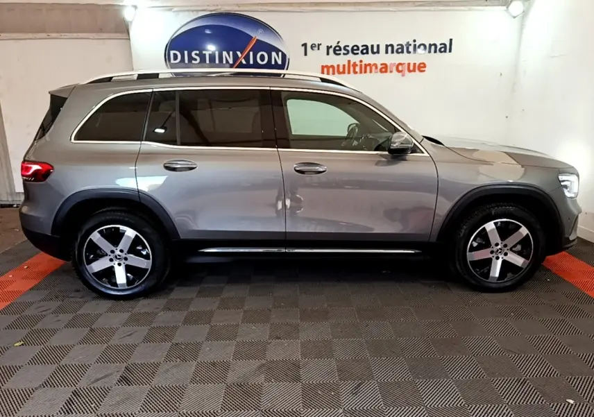Vue de profil côté droit d’un Mercedes GLB 200 d Business Line gris foncé dans un showroom multimarque.